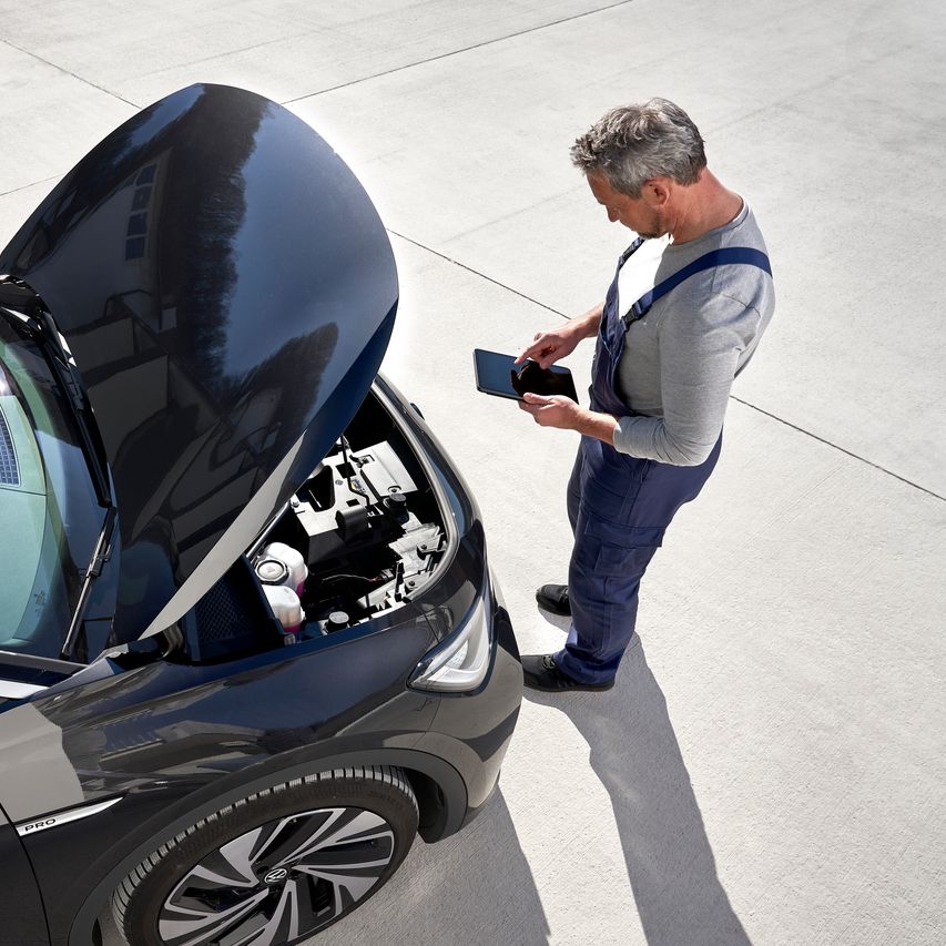 Volkswagen Service Techniker vor geöffneter Motorhaube